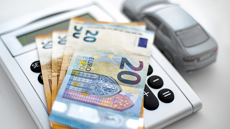 calculadora, notas de euro e carro numa mesa